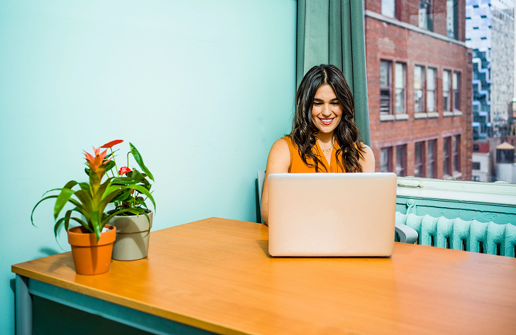 Photo d'une femme qui travaille sur son bureau en bois avec deux pots de fleurs